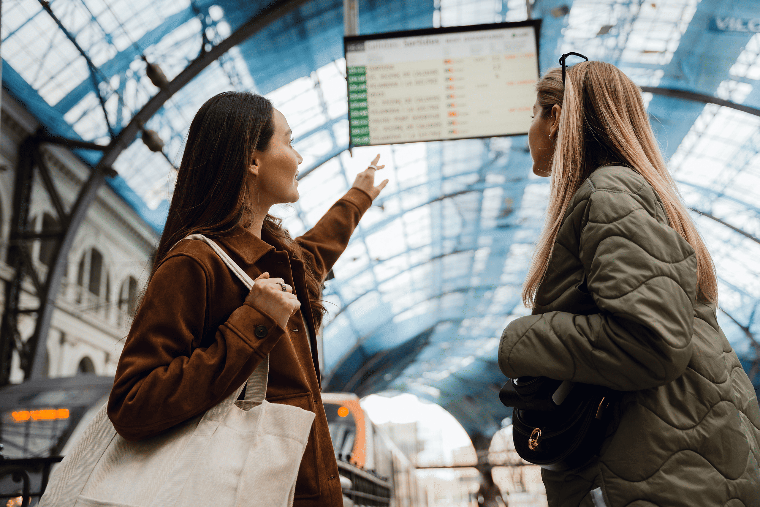 Two travellers checking the departures board in a station